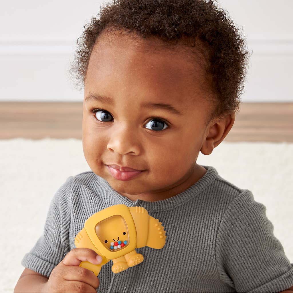 Child holding a yellow toy with a smiling face, wearing a gray sweater.
