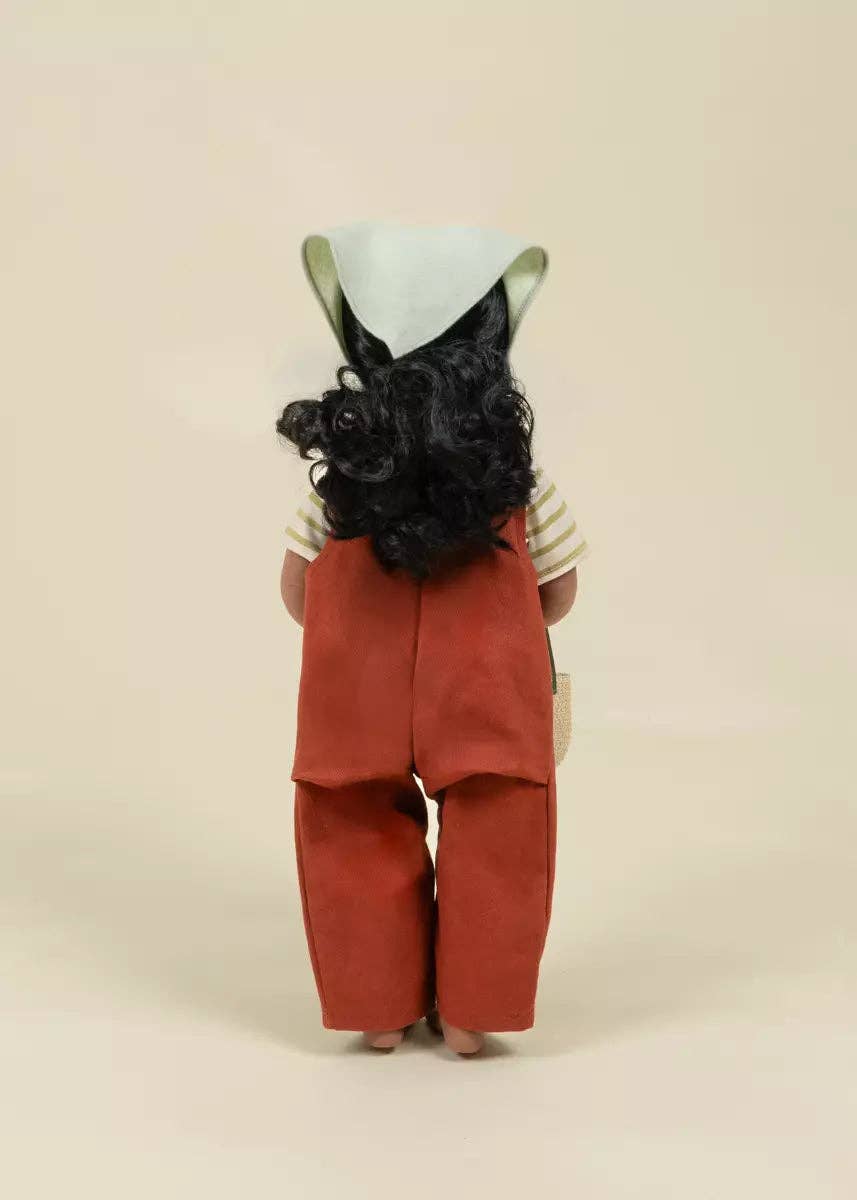 Doll with a cone-shaped hat and red overalls on a beige background