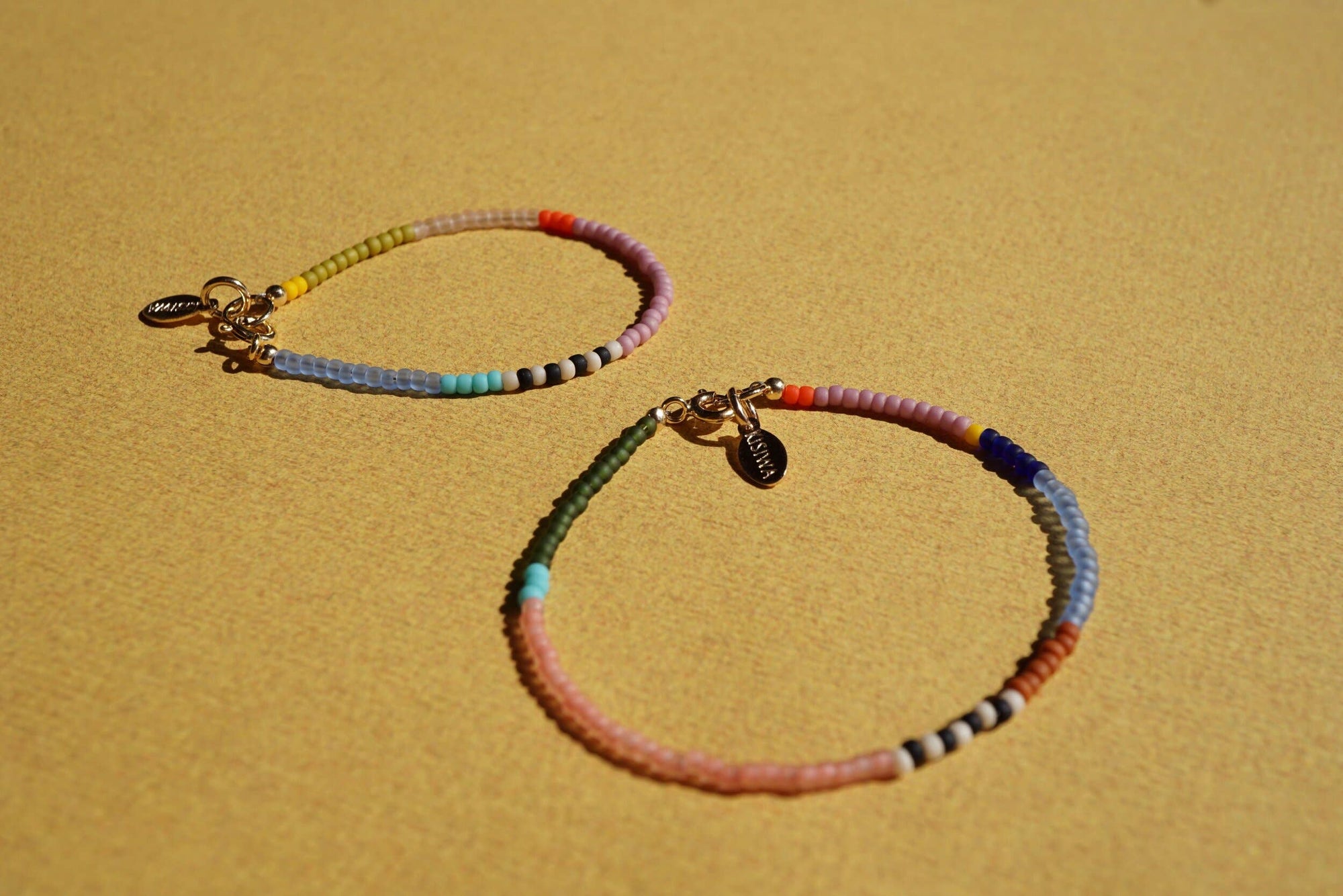Two colorful beaded bracelets on a beige surface