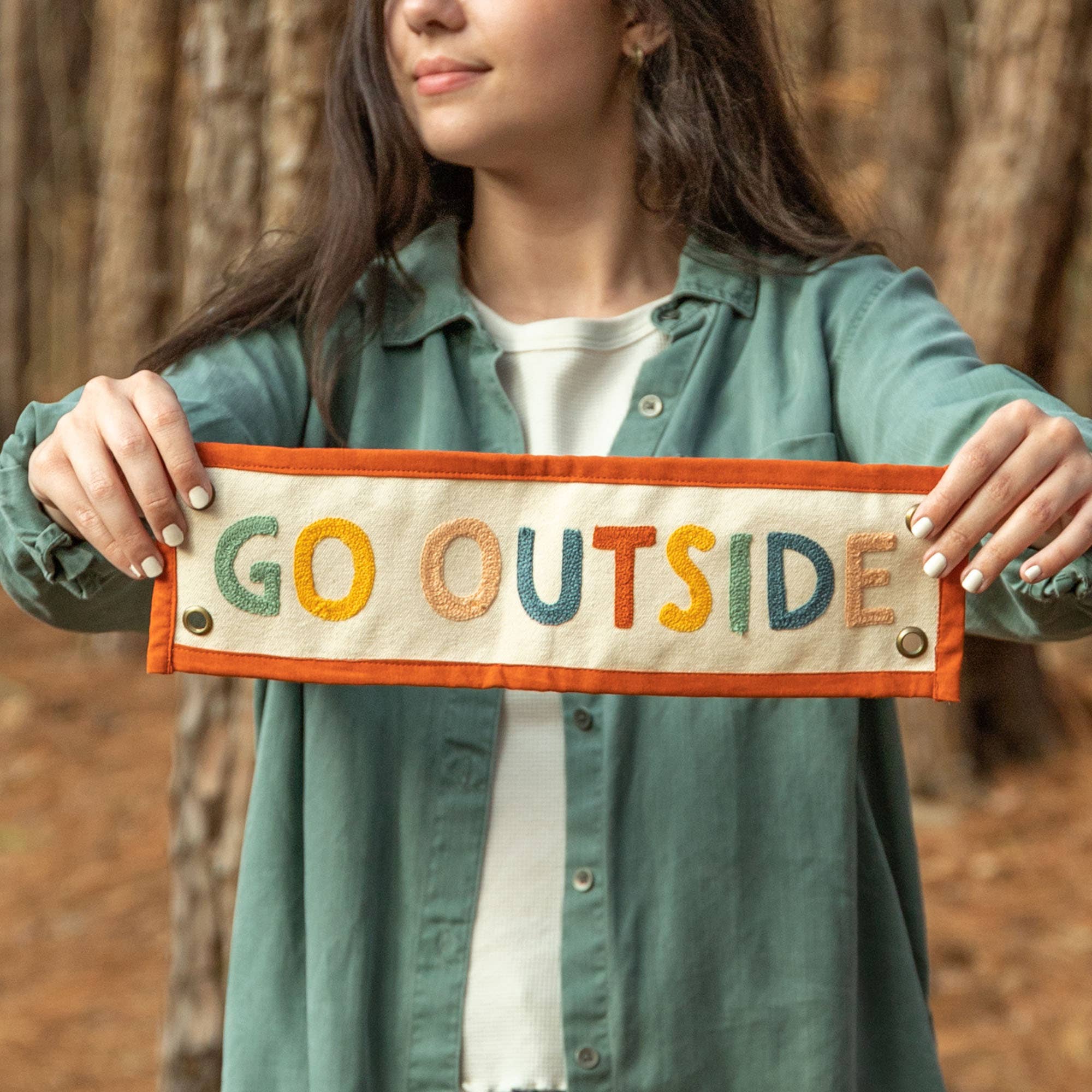 Person holding a sign with 'GO OUTSIDE' text in an outdoor setting