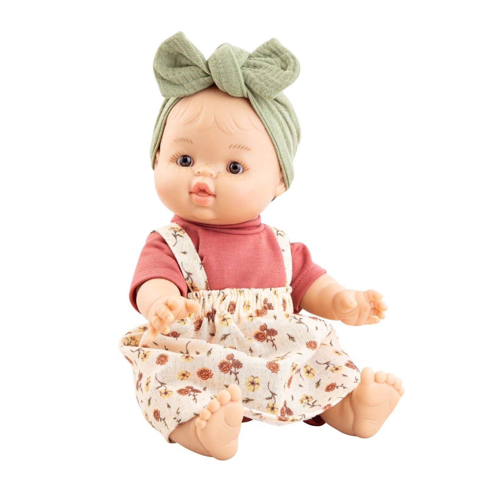 Baby doll with a floral dress and green headband on a white background