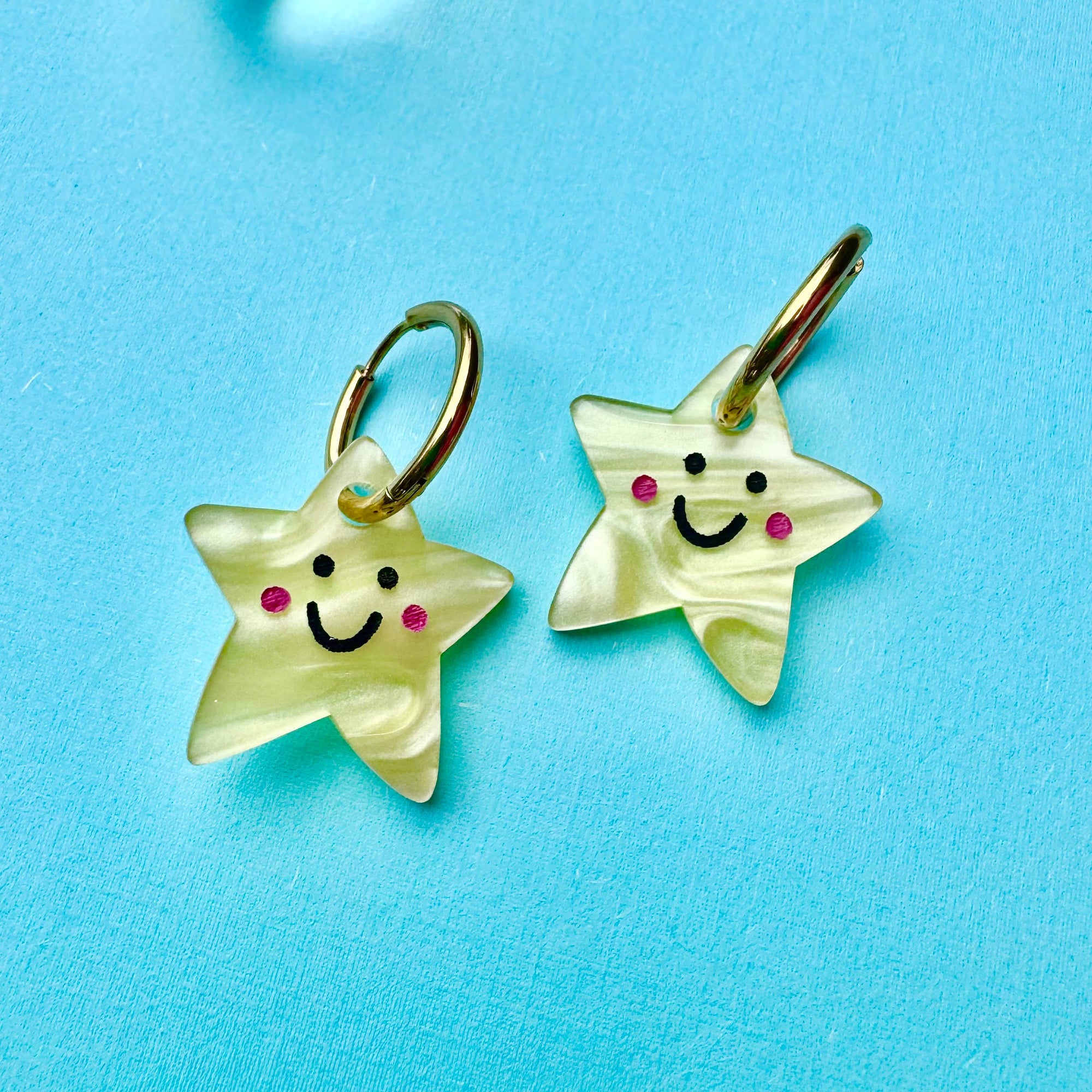 Star-shaped earrings with smiley faces on a blue background