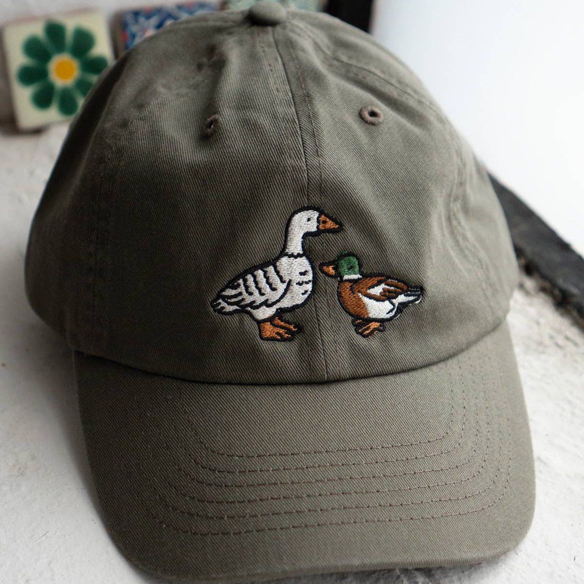Green cap with embroidered geese design on a textured surface