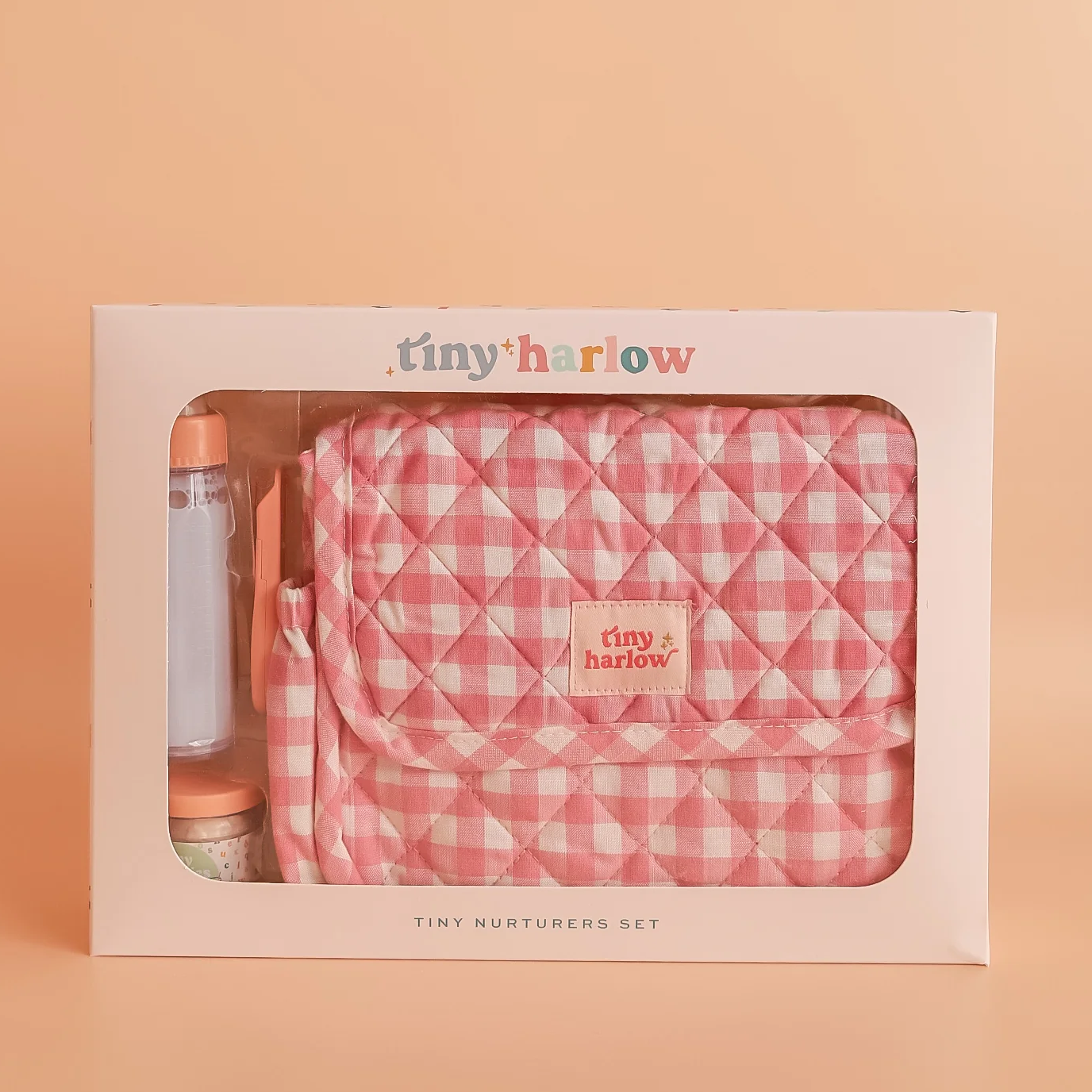 Tiny Harlow baby product set in packaging on a peach background