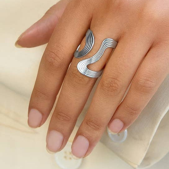 Silver ring on a finger against a neutral background