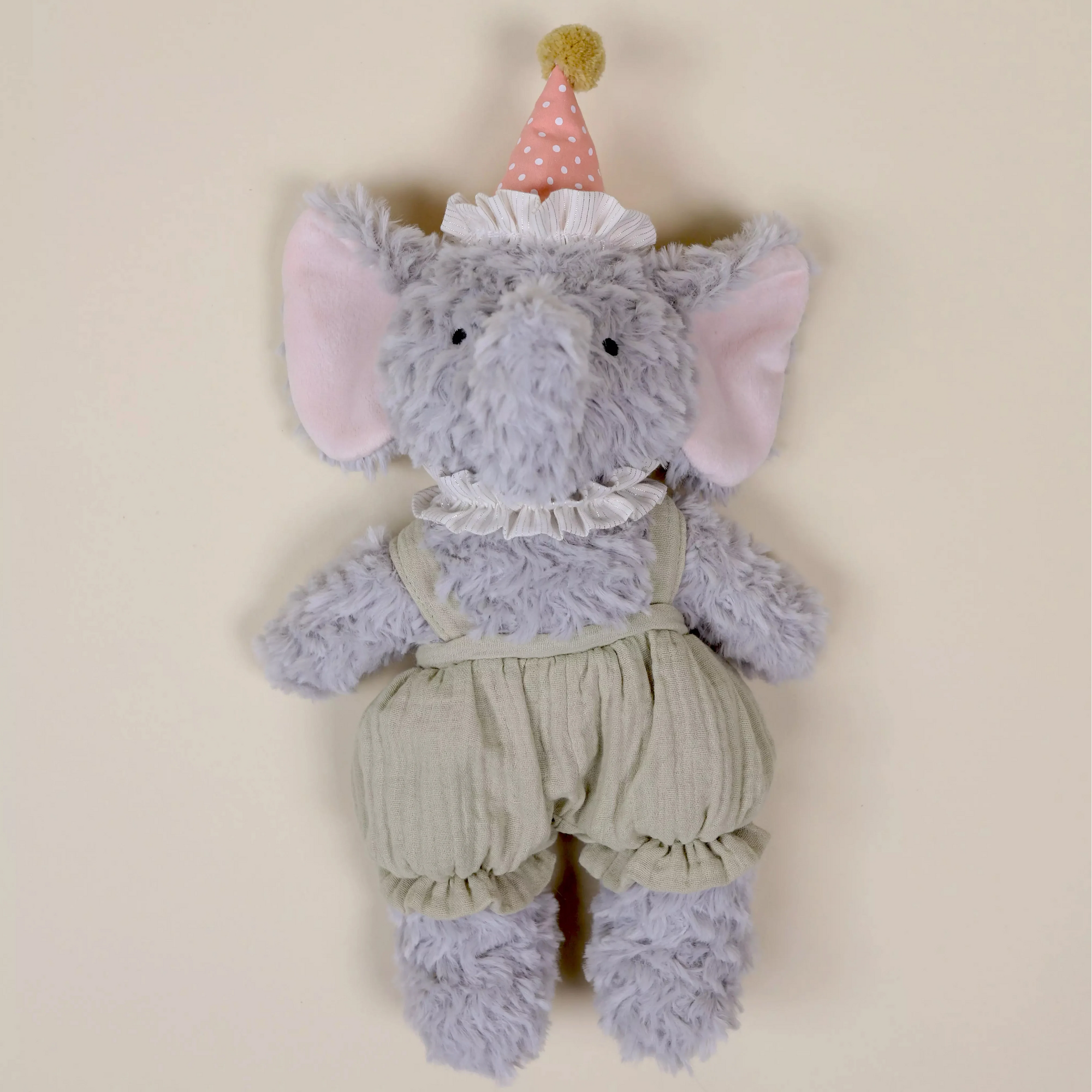 Stuffed elephant toy with a party hat on a beige background