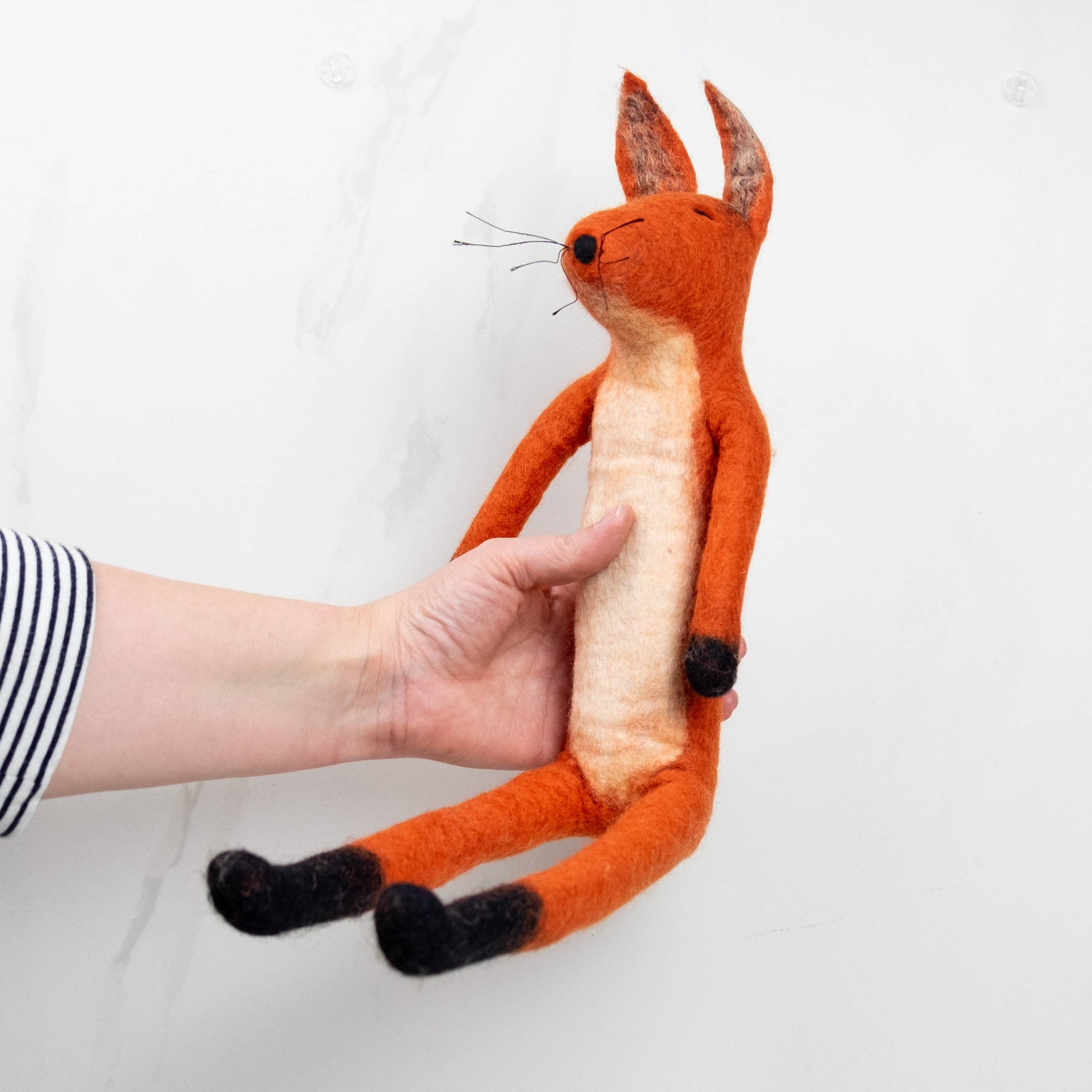 Hand holding a plush fox toy against a white background