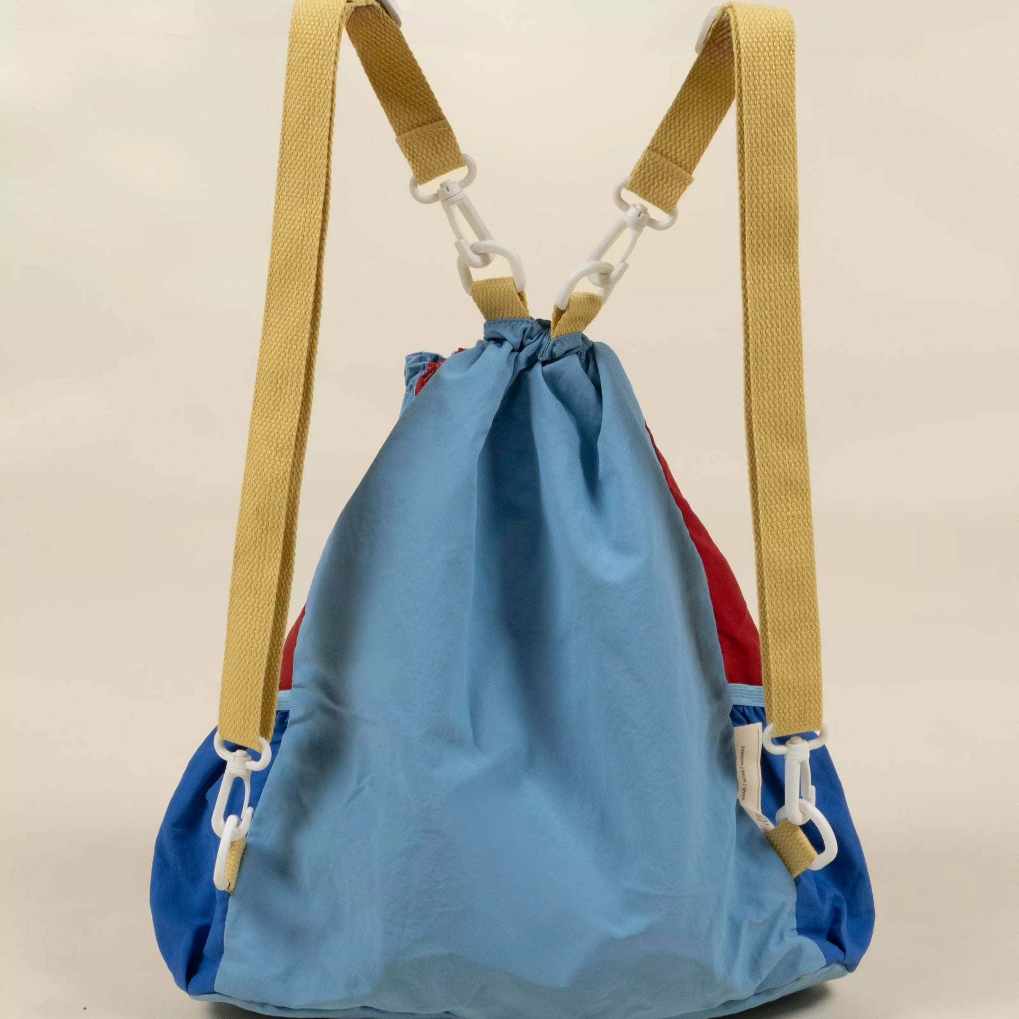 Blue drawstring bag with beige straps on a beige background
