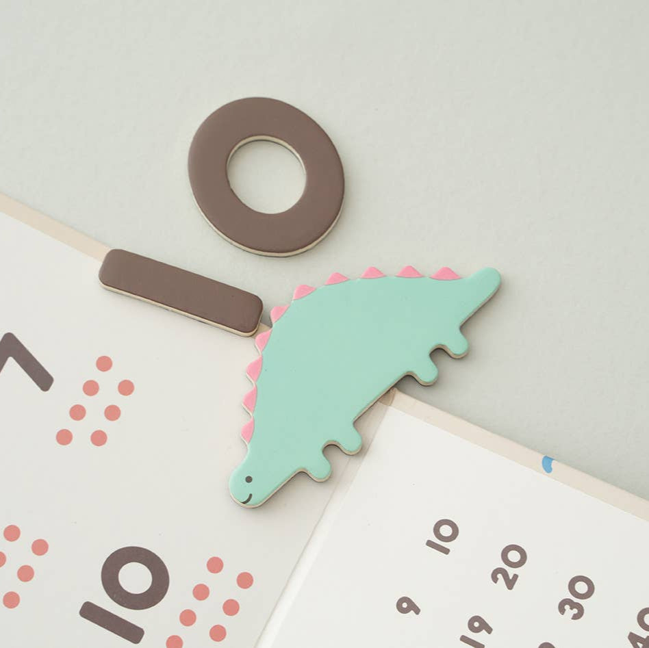 Educational tools including a green puzzle piece, brown clip, and number cards on a light gray background.