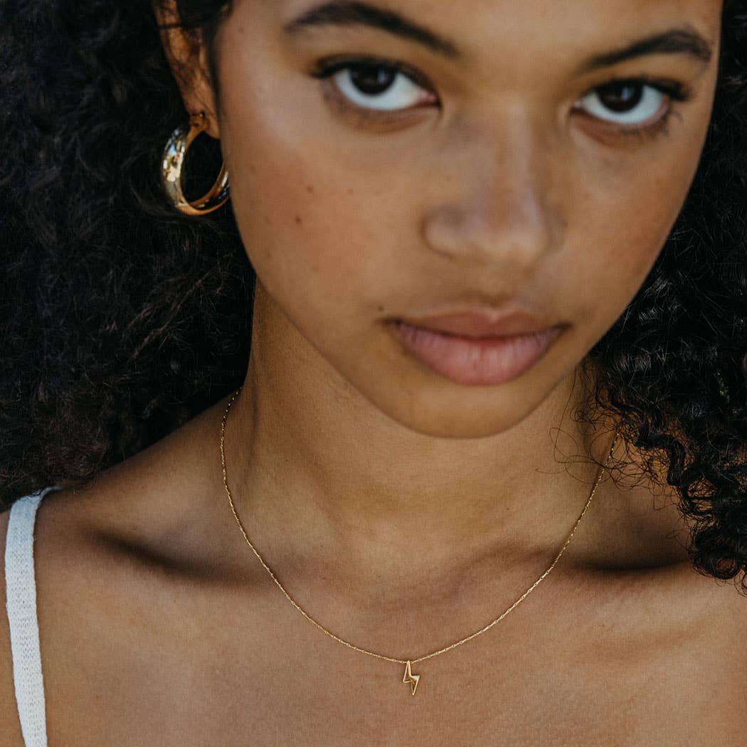 Close-up of a woman wearing a gold necklace with a small pendant.