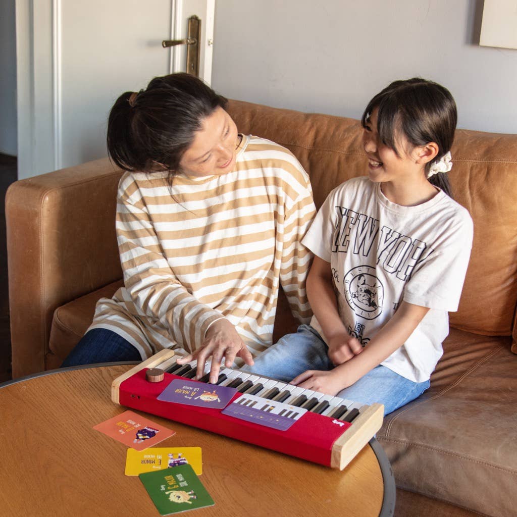 Two people playing a small keyboard on a couch