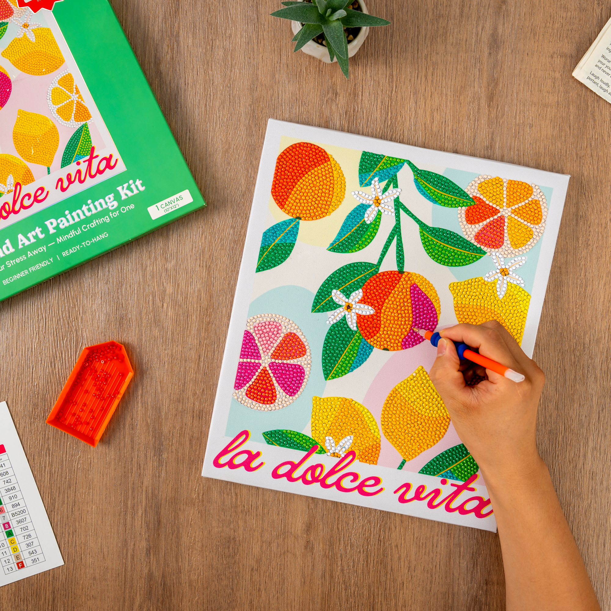 Coloring book with 'la dolce vita' design on a wooden table, surrounded by art supplies.