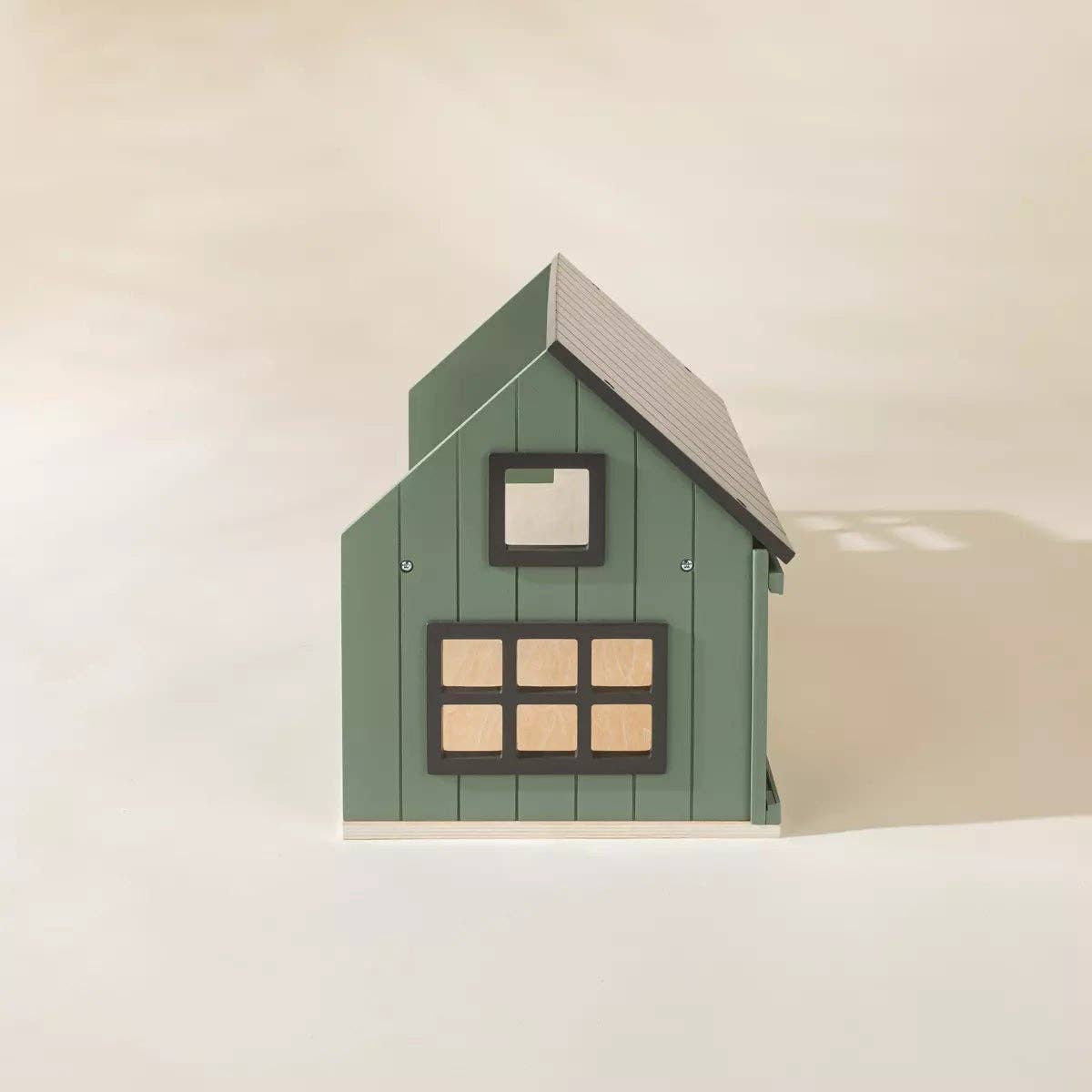 Green toy house with a white roof on a beige background