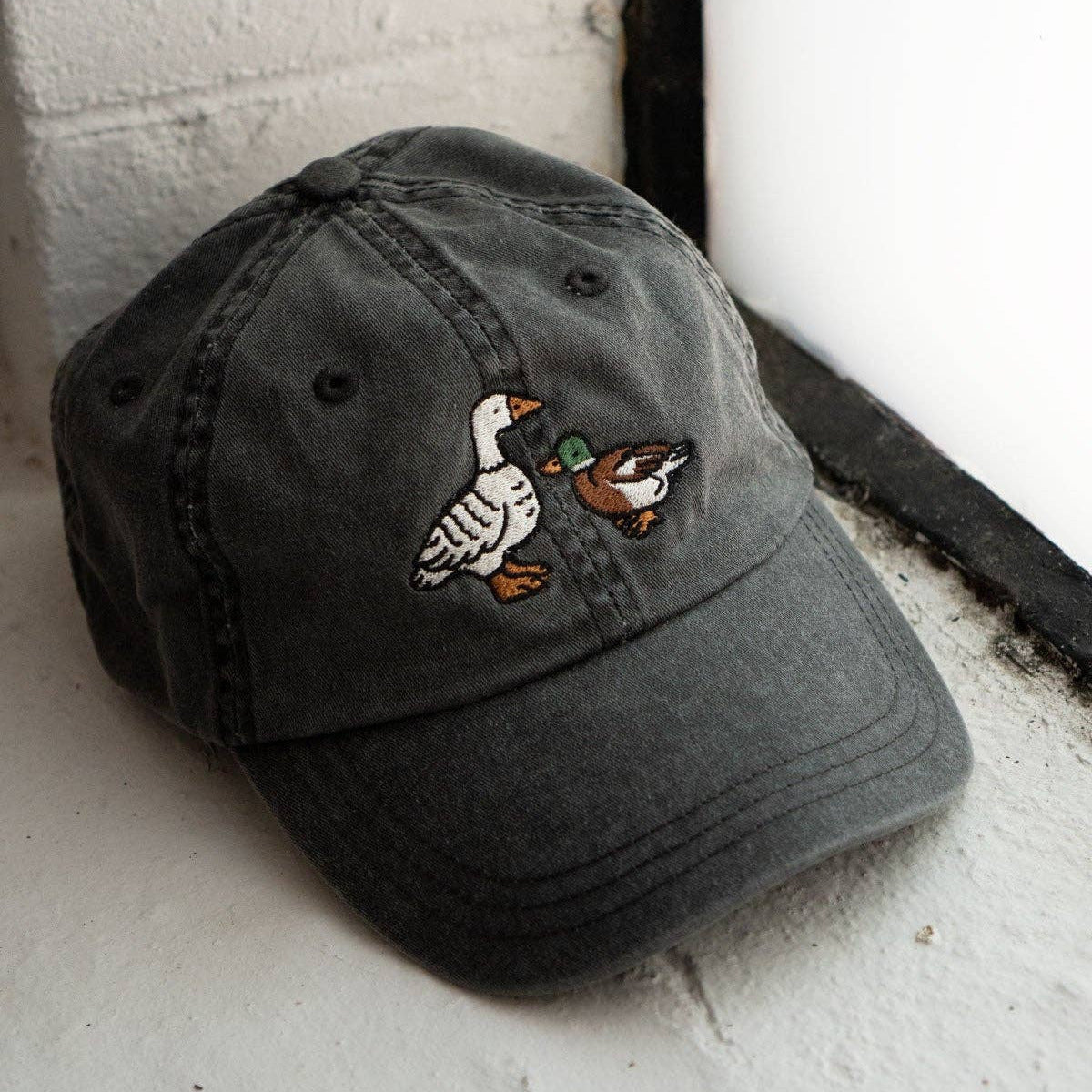 Gray cap with duck embroidery on a white surface