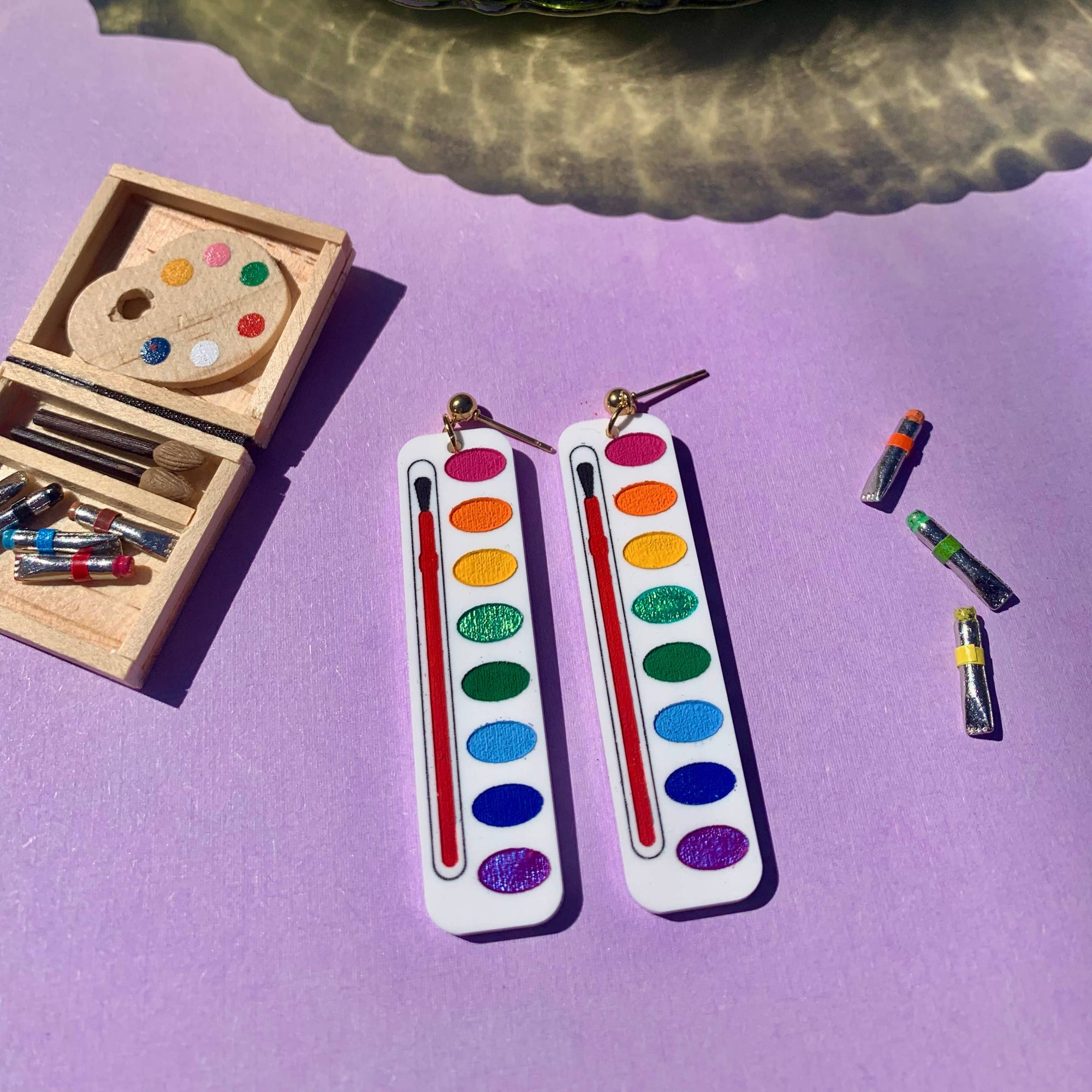 Colorful bookmarks with paint palette and brushes on a purple surface