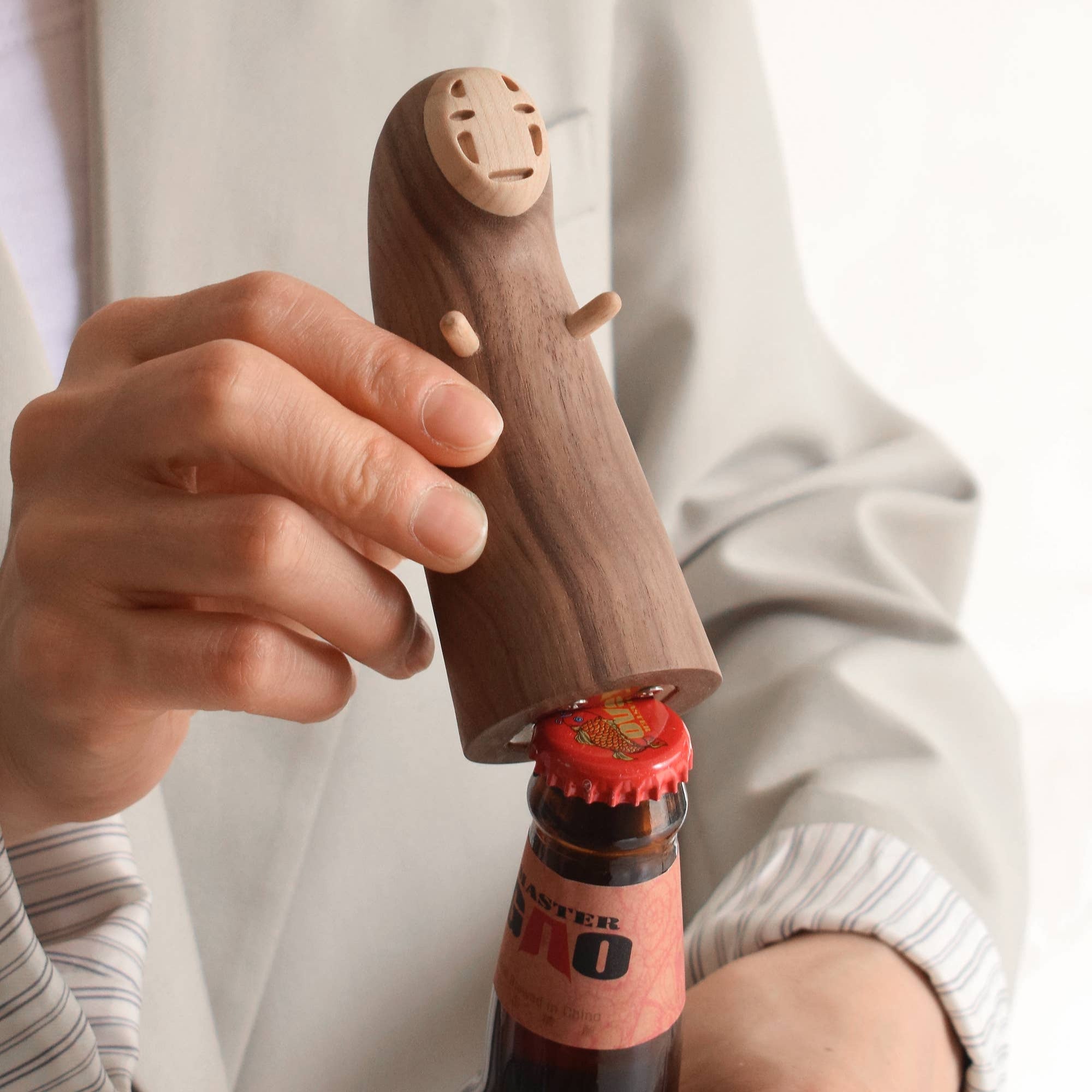 Person using a wooden bottle opener on a bottle