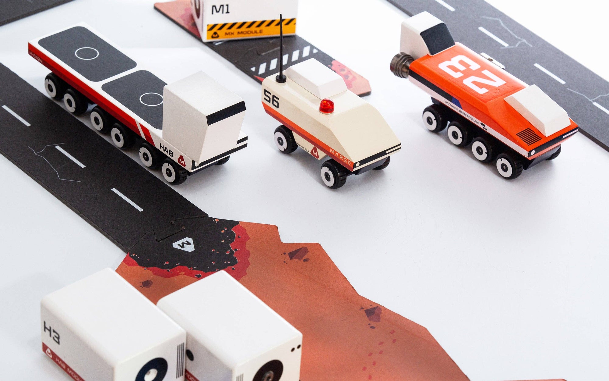 Toy vehicles on a road with a scenic background