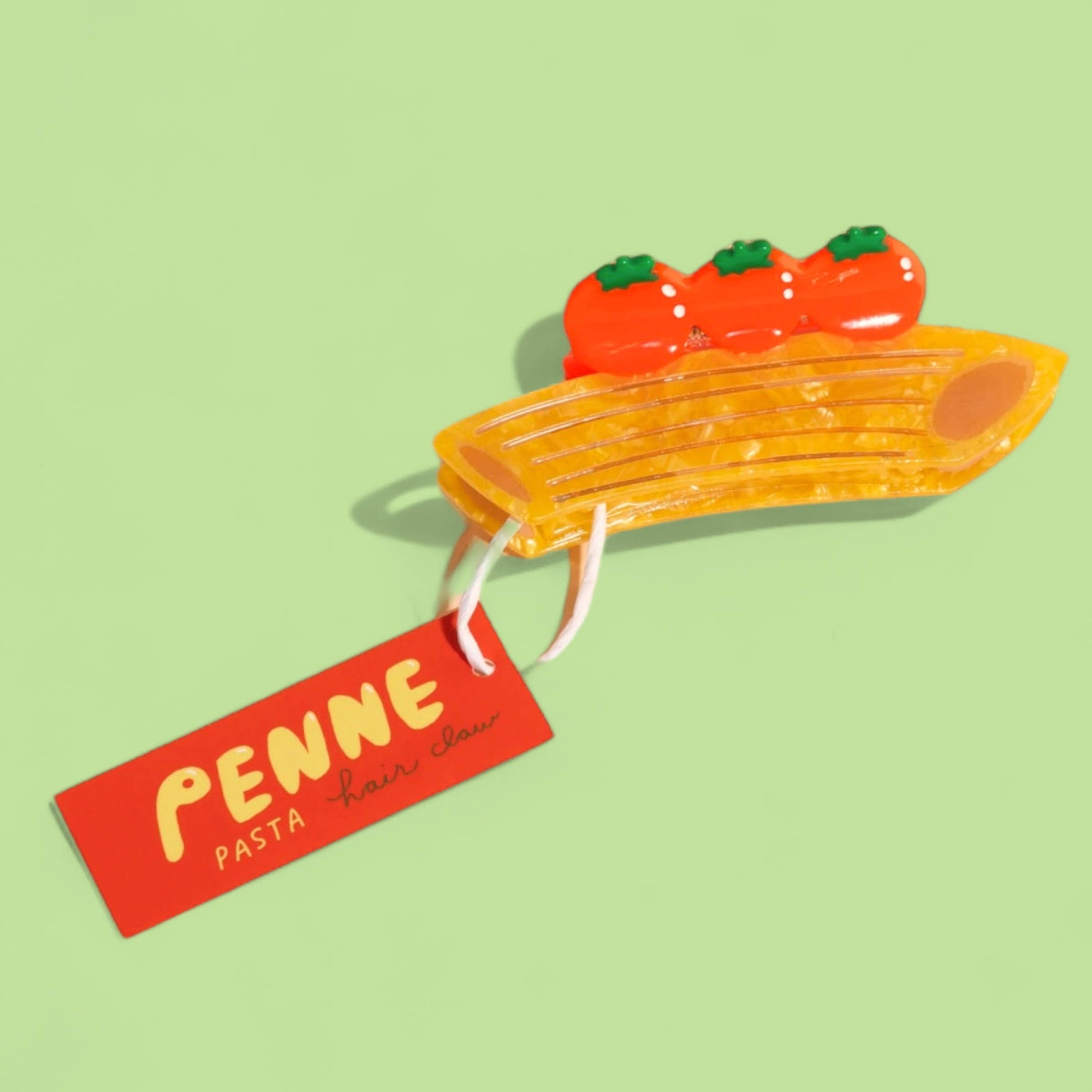 Penne pasta toy with cherry tomatoes on a green background