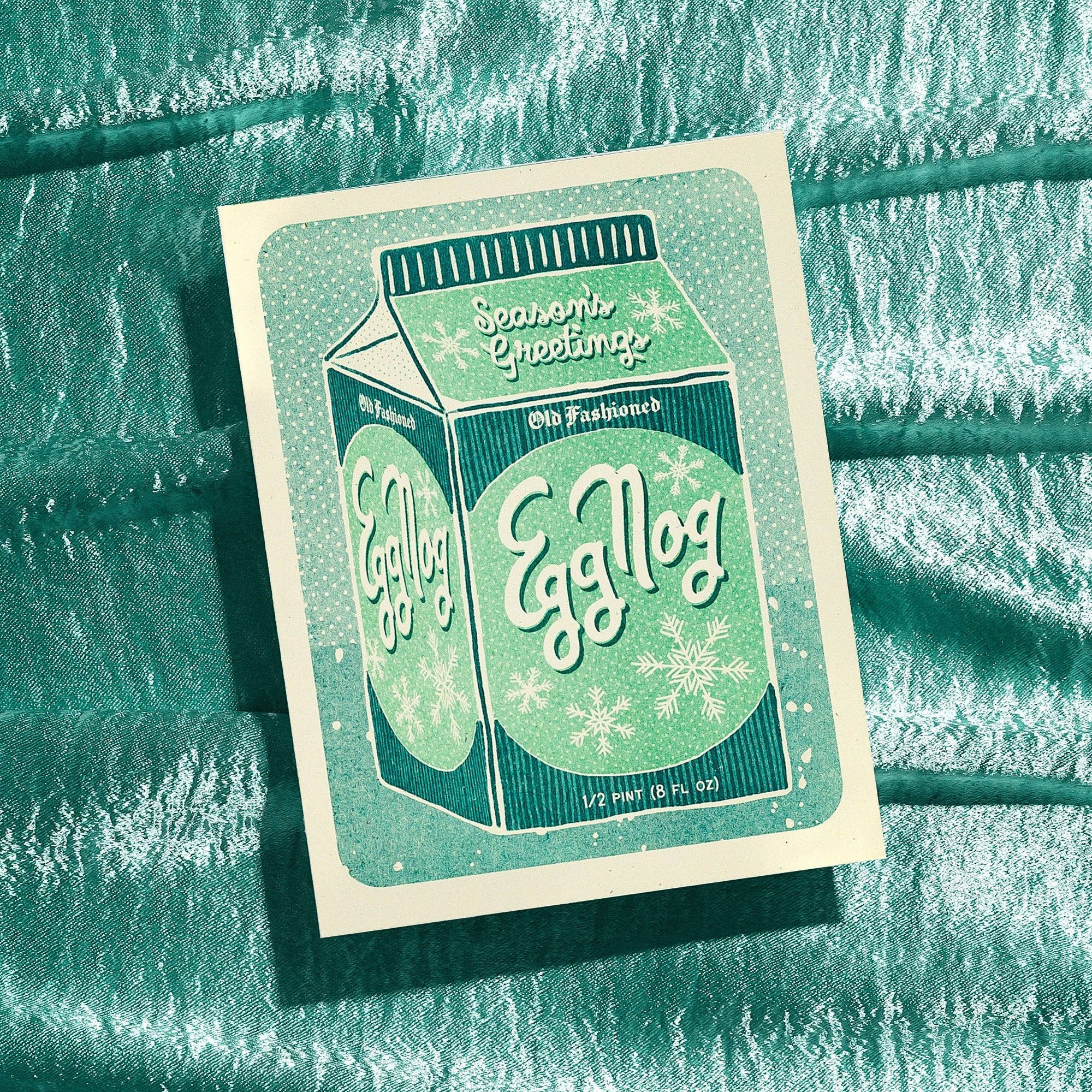 Card with a vintage-style egg nog box design on a textured green background