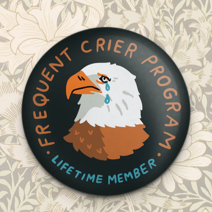 A round black magnet featuring an illustration of an eagle with a teardrop, alongside text that reads 'Frequent Crier Program' and 'Lifetime Member'.