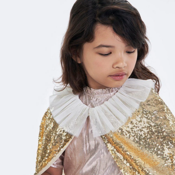 little girl wearing sparkly gold cape with white tulle collar 