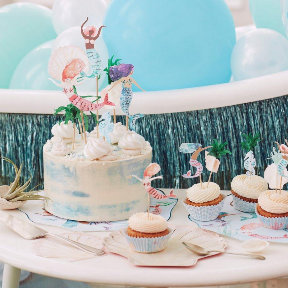 3 mermaids, two shells, a seahorse and tissue grass on long wooden sticks in a cake at a mermaid themed party