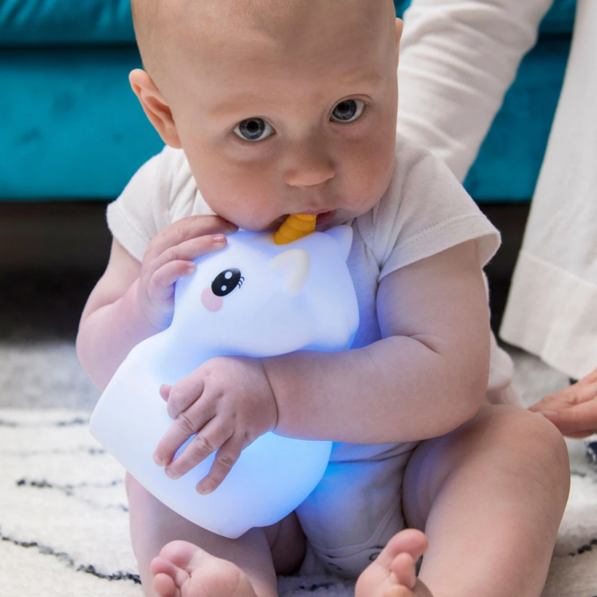 baby holding blue lit up unicorn