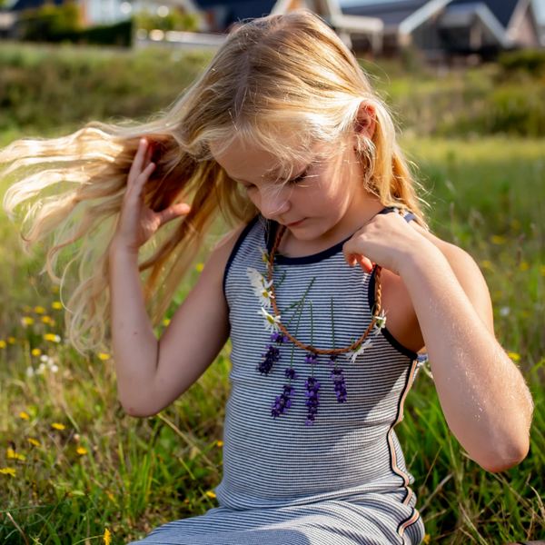 little girl looking down at necklace with flowers she's wearing