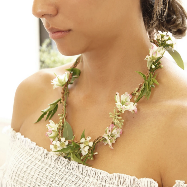 woman wearing flower necklace with white dress