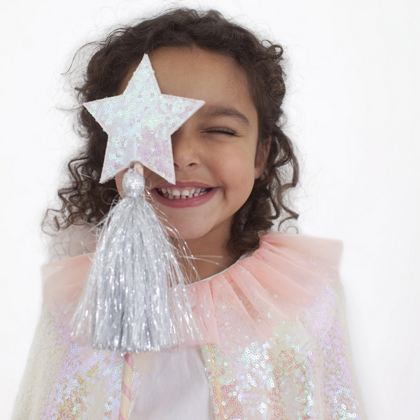 pink sequin cape worn by little girl who is holding sequined star wand with silver tassle up to eye