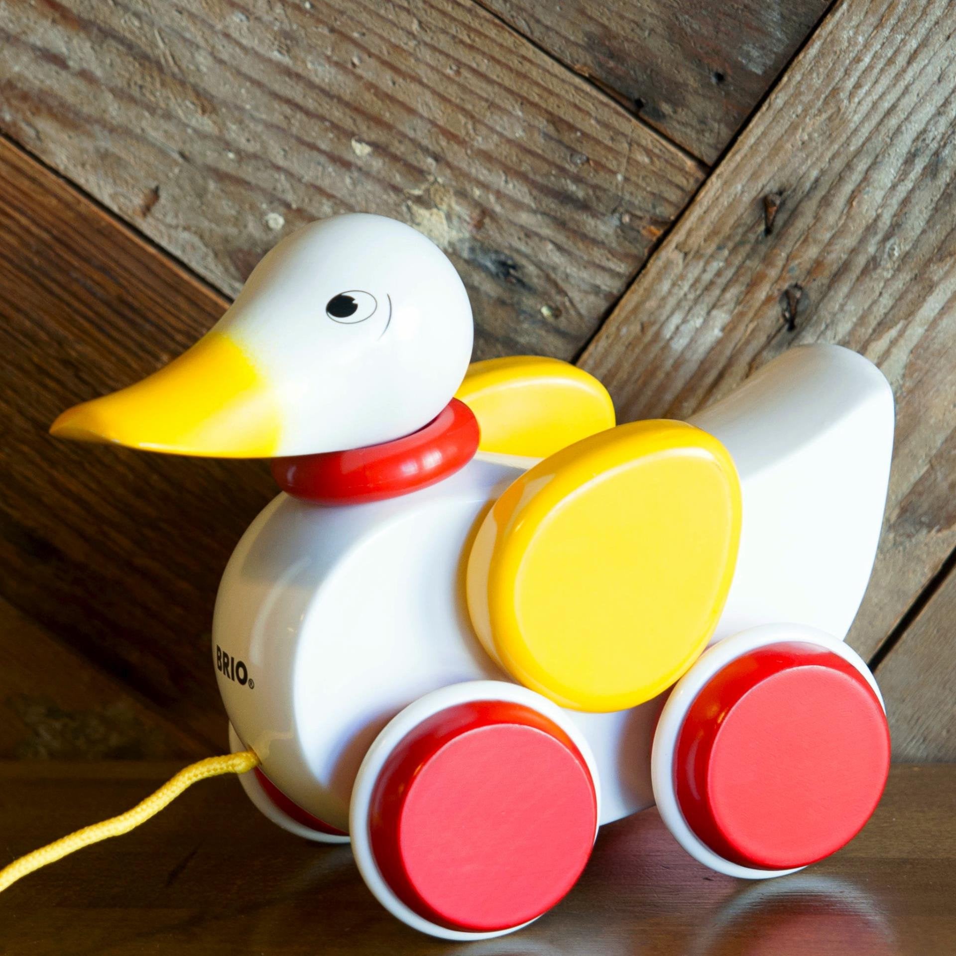 wooden yellow, white and red pull along duck on wooden background