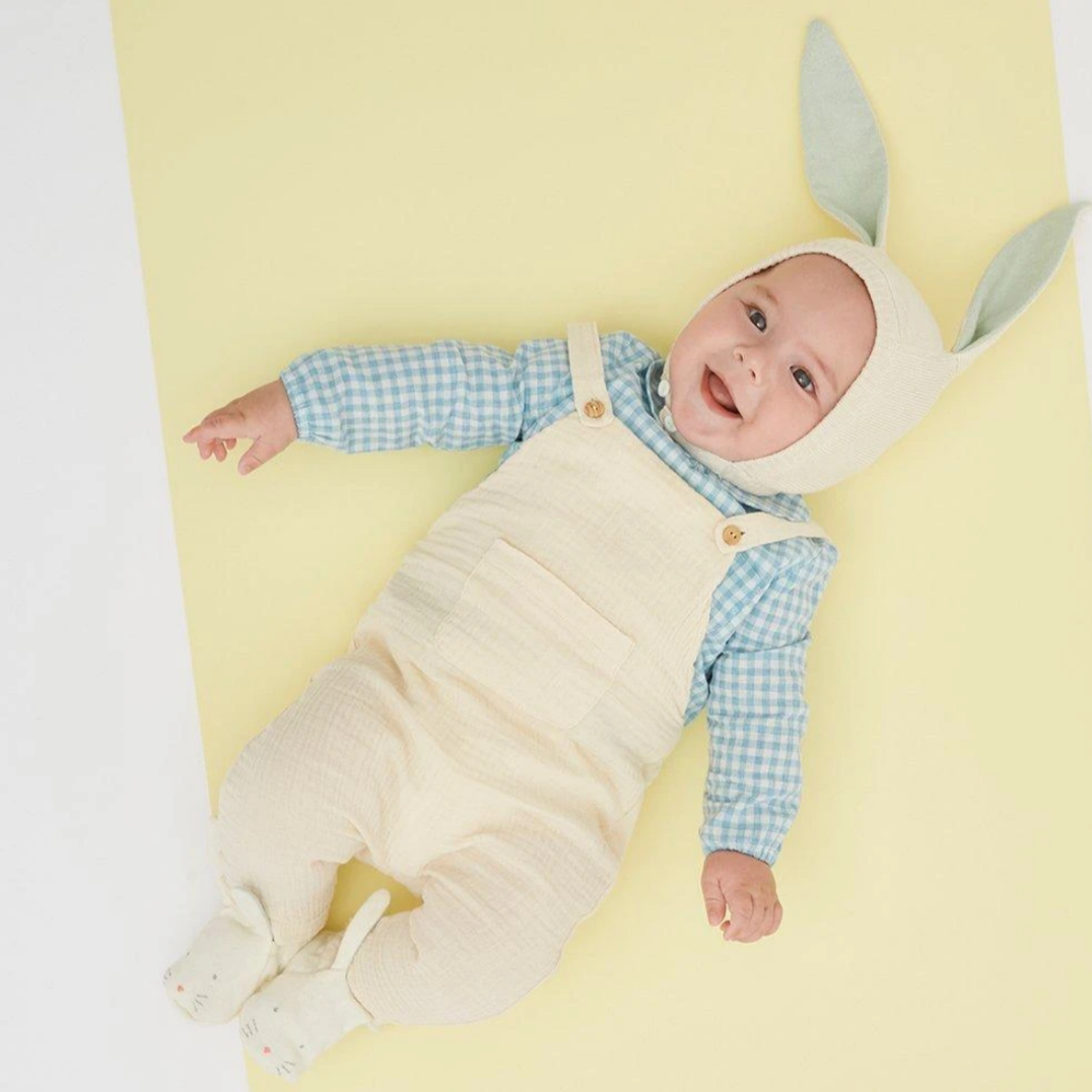 baby dressed in overalls wearing bunny hat