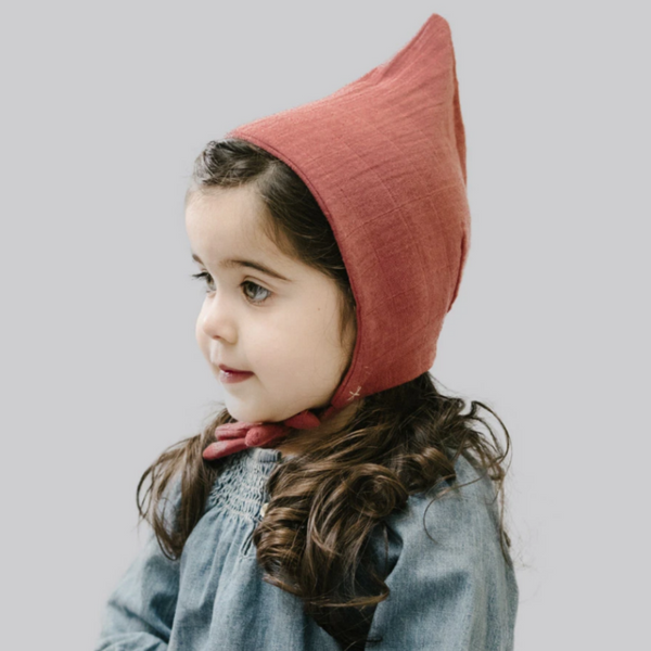 little girl wearing light red pixie bonnet