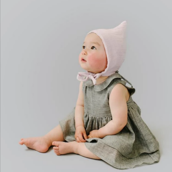 baby girl wearing grey dress and lilac pixie bonnet