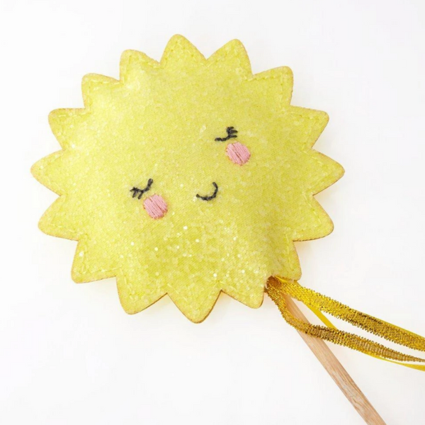 detail of sparling yellow sun with face on top of wooden wand