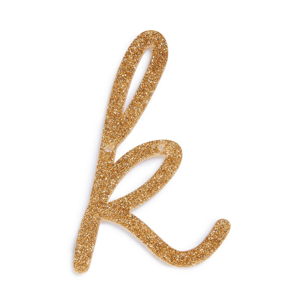 lowercase cursive k in gold acrylic with small holes to hang it.