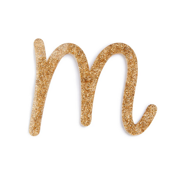 lowercase cursive m in gold acrylic with small holes to hang it.