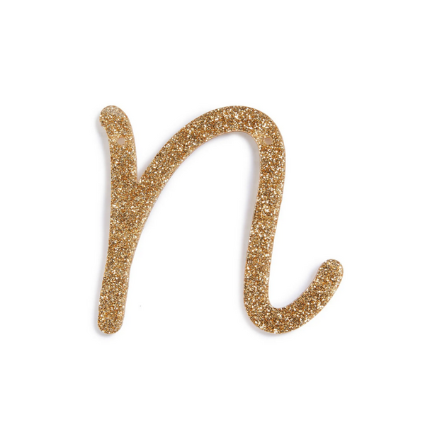 lowercase cursive n in gold acrylic with small holes to hang it.