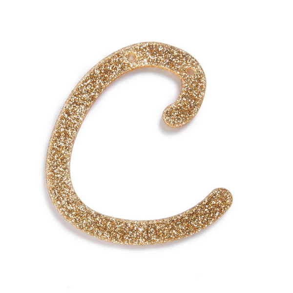 lowercase cursive c in gold acrylic with small holes to hang it.