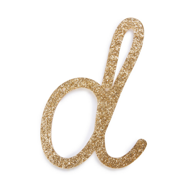 lowercase cursive d in gold acrylic with small holes to hang it.