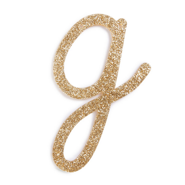 lowercase cursive g in gold acrylic with small holes to hang it.