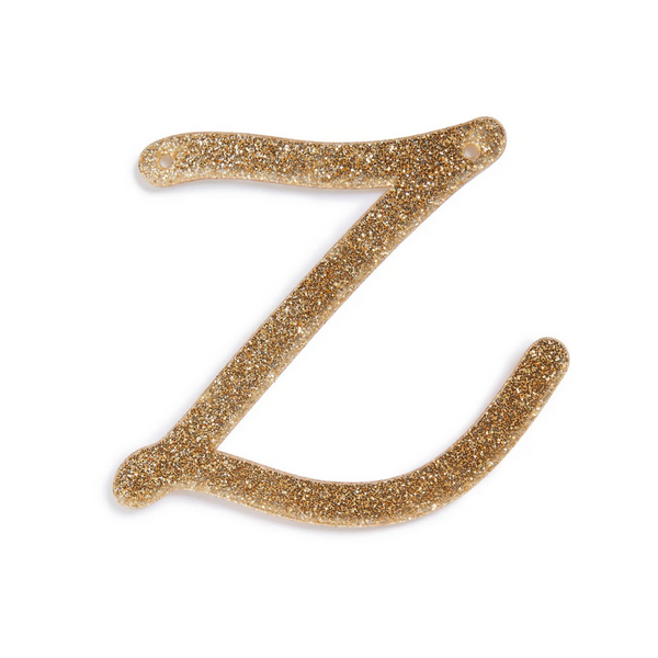 lowercase cursive z in gold acrylic with small holes to hang it.