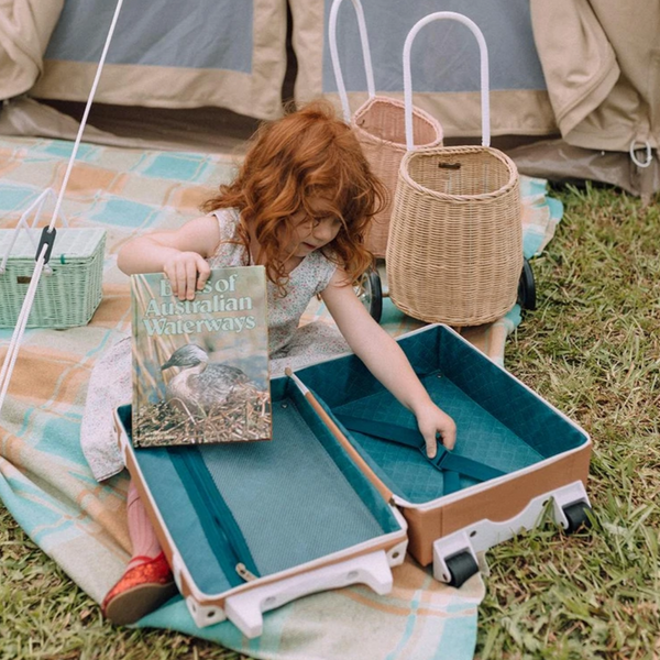 picture of baskets behind kid playing with suitcase
