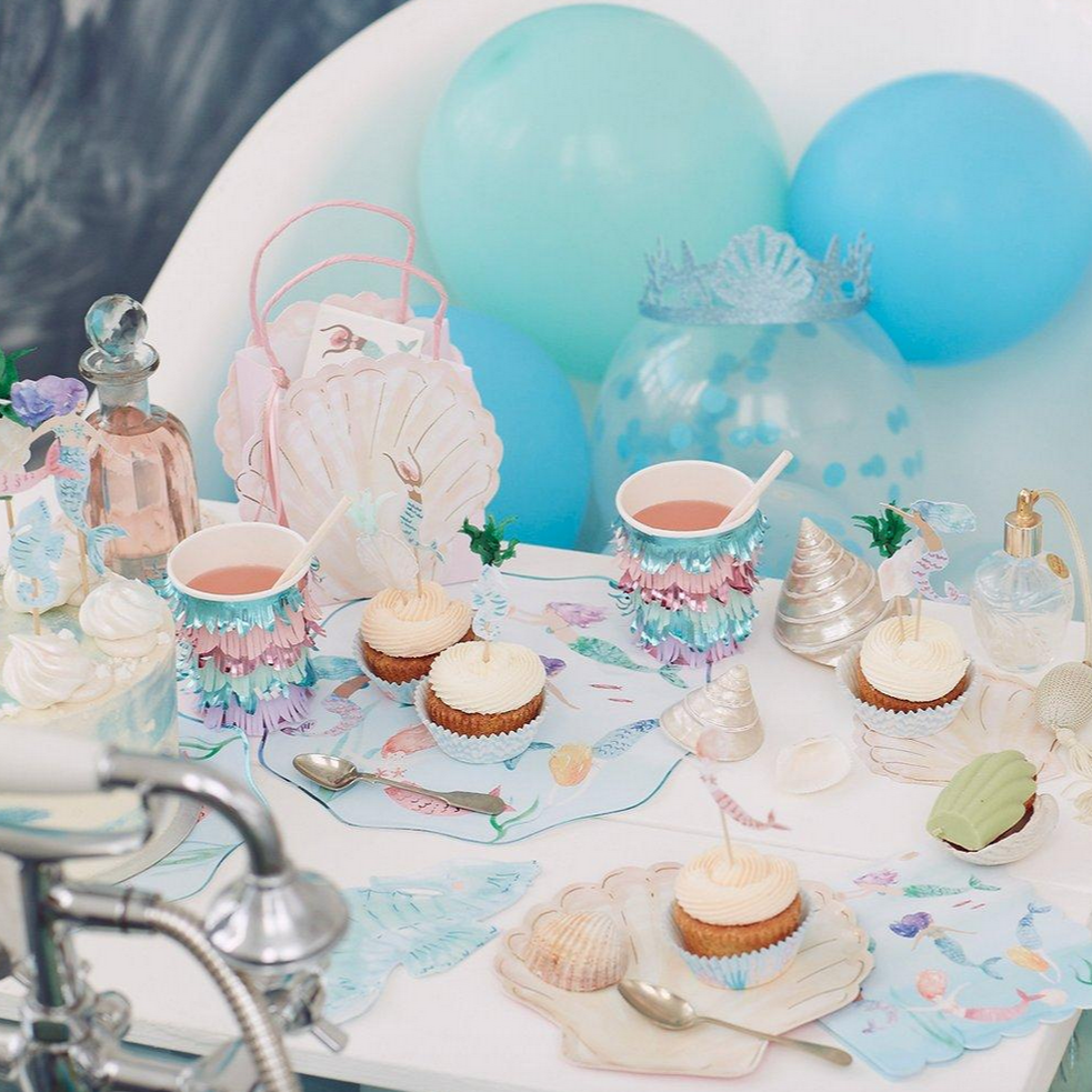 birthday party scene with cups and cupcakes on table 