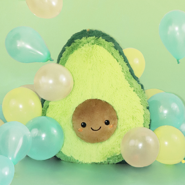 avocado plush with face on pit surrounded by balloons