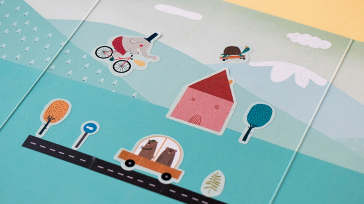 page of book with stickers on green pastures with mountains behind them