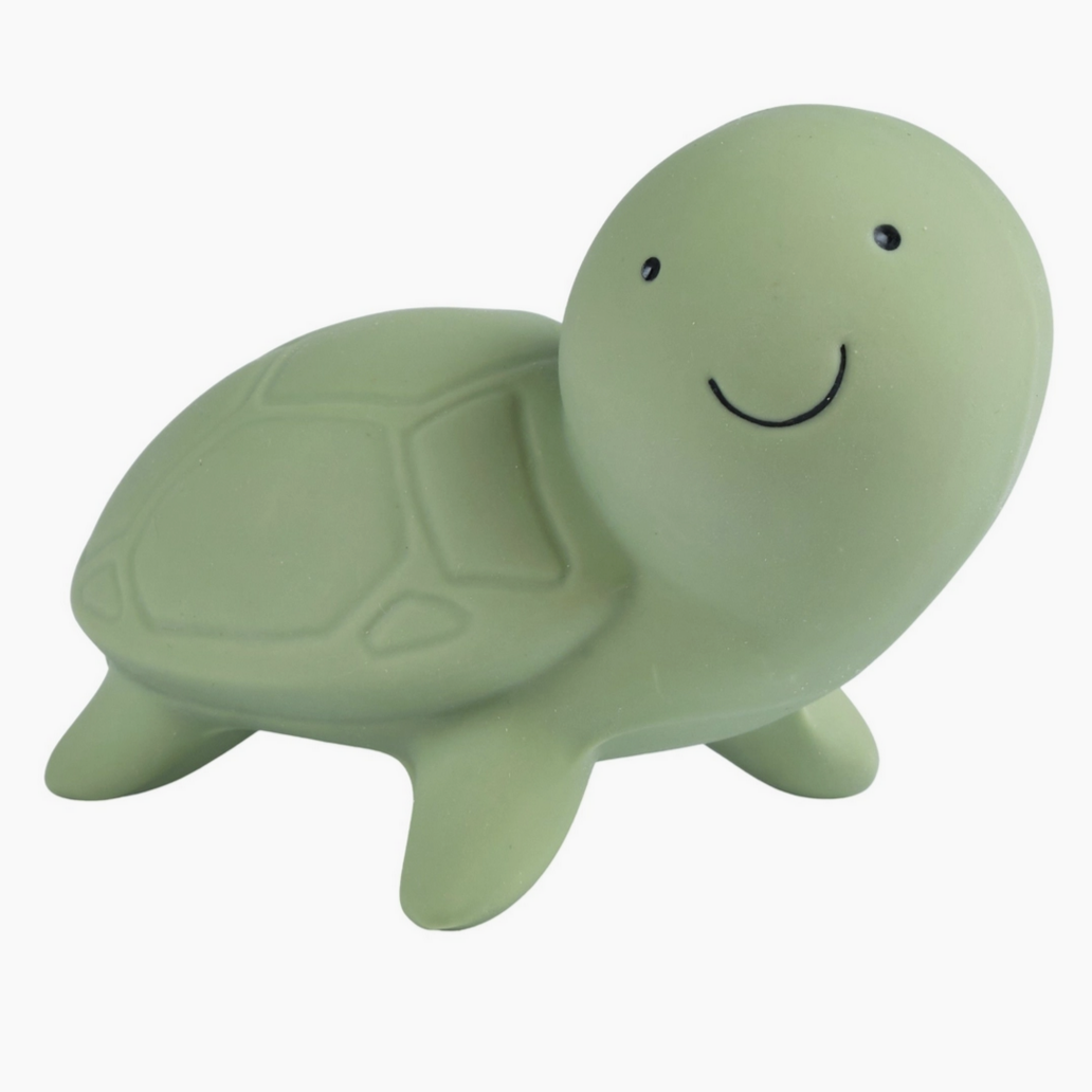 A natural rubber turtle teether, rattle, and bath toy with a smiling face.