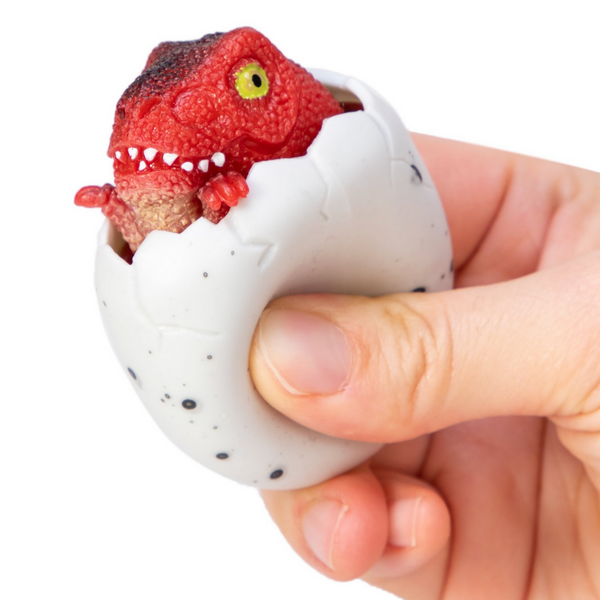 red baby dinosaur peeking out of egg that's being squeezed by a hand
