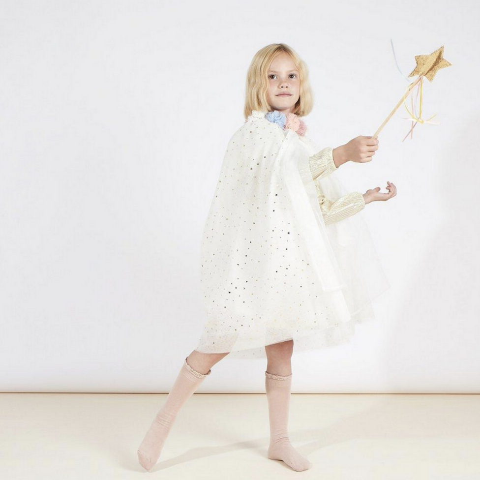 little girl wearing sparkly white cape holding wand with star