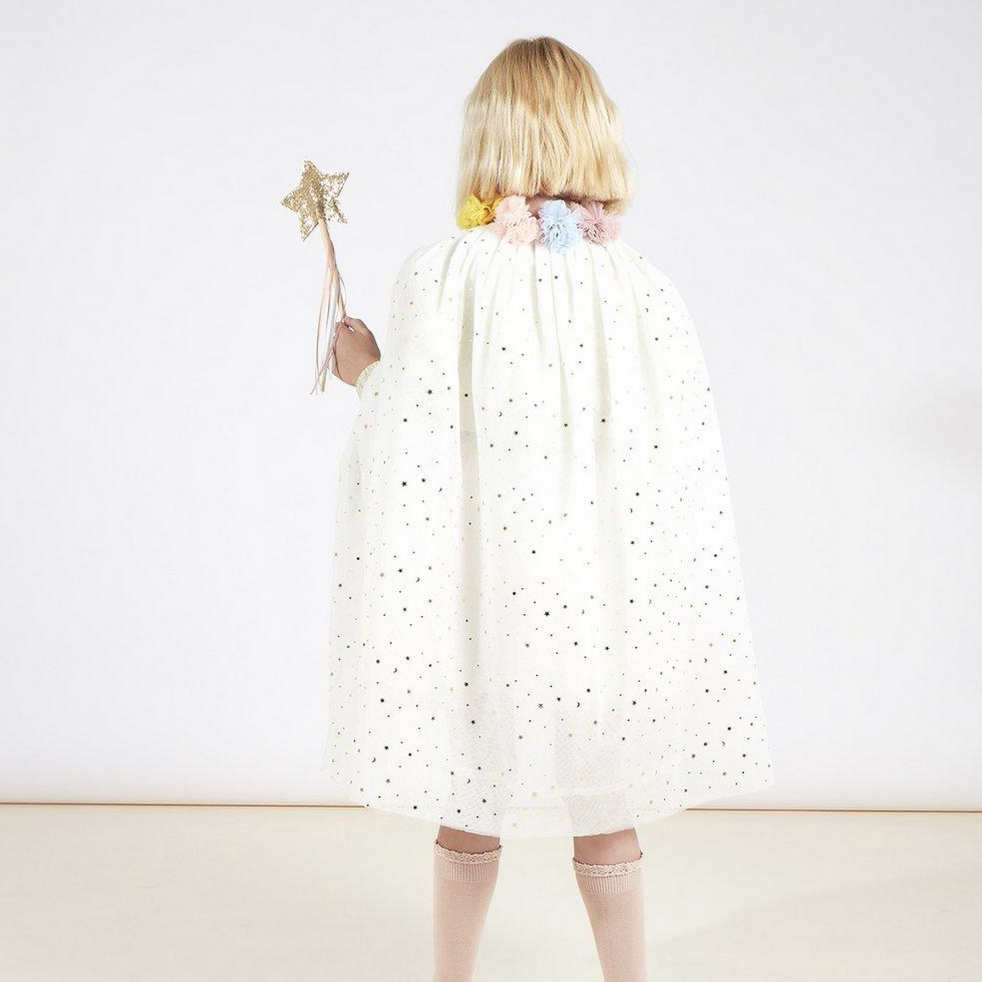 back of little girl wearing sparkly white cape holding wand with star